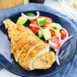 Baked chicken cutlets on blue plate with salad.