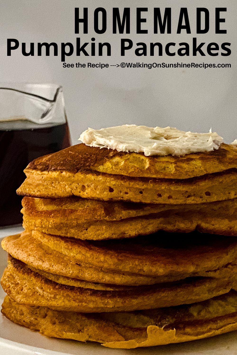 Stack of homemade pumpkin pancakes topped with butter and syrup in a pitcher to the side.