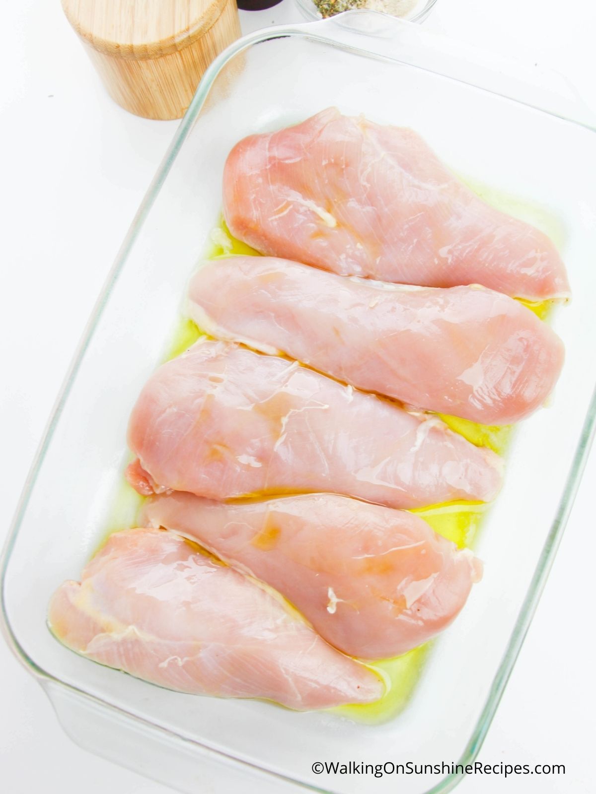 Raw chicken cutlets in baking dish.