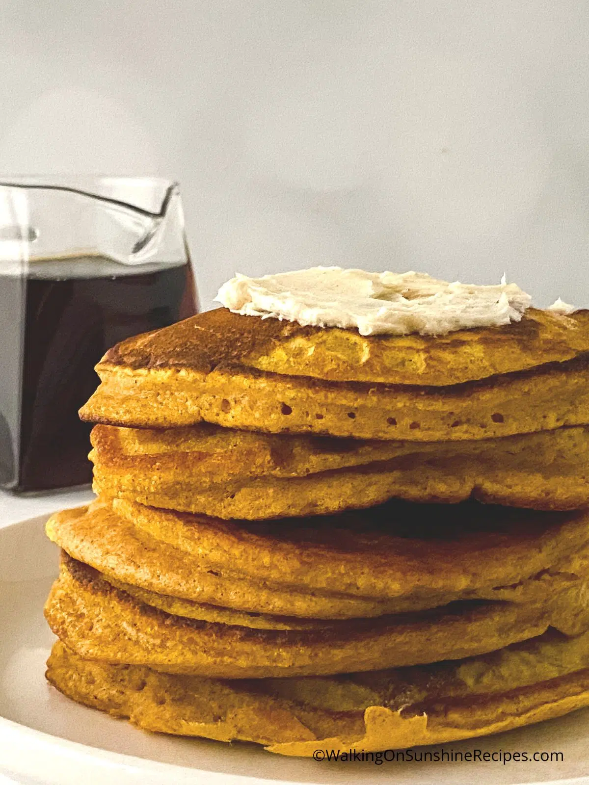 Stacked pumpkin pancakes with maple syrup.