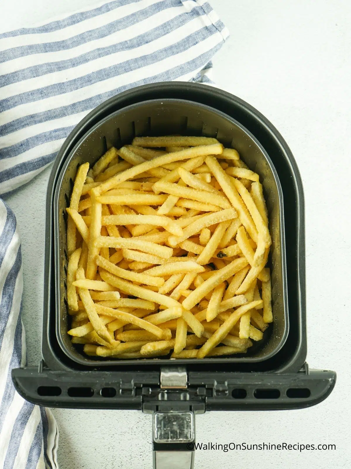 French fries in air fryer basket before baking.