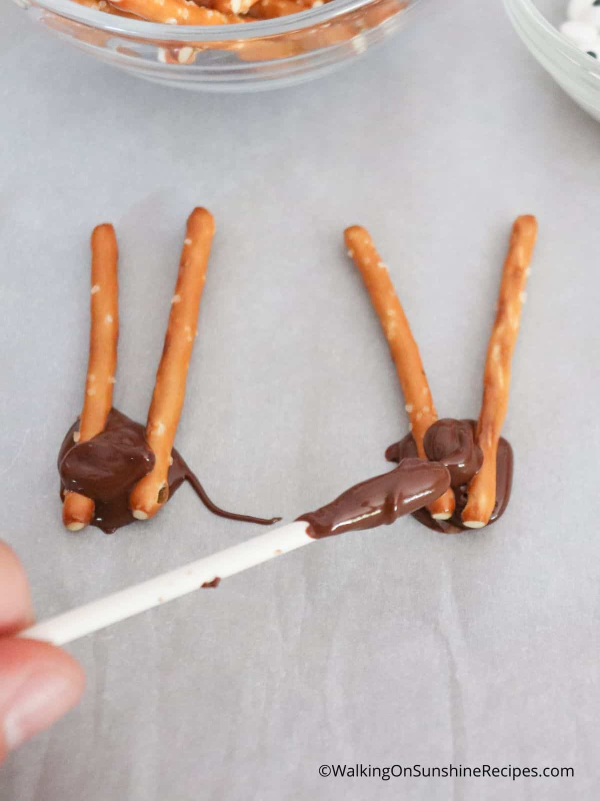 https://walkingonsunshinerecipes.com/wp-content/uploads/2022/08/3-attach-the-antlers-together-with-the-melted-chocolate.-.jpg