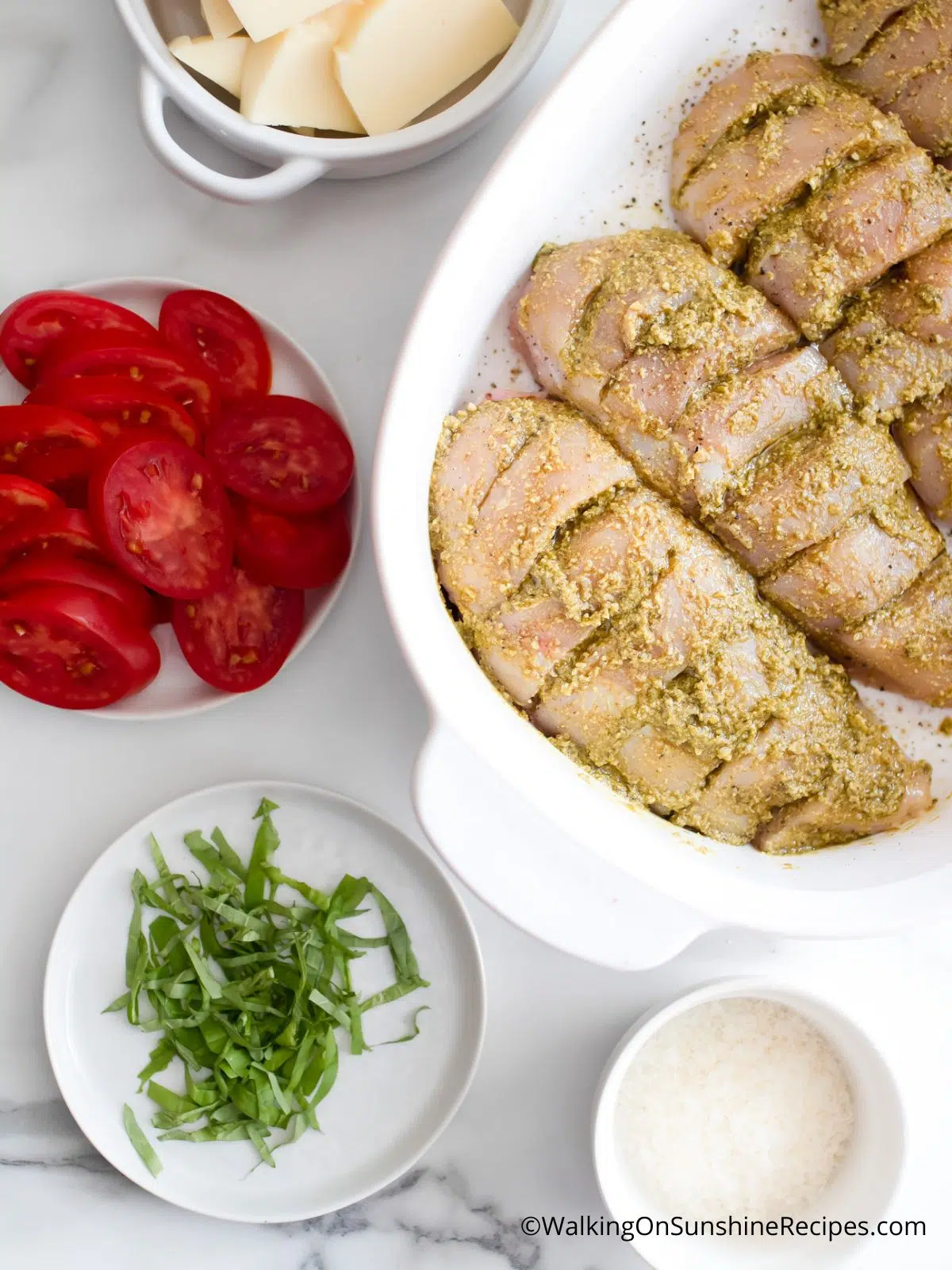 Chicken with basil pesto sauce in casserole dish.