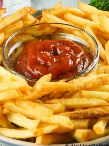 French fries on a plate with ketchup in the center.