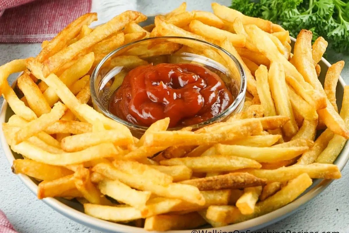 French fries on a plate with ketchup in the center.