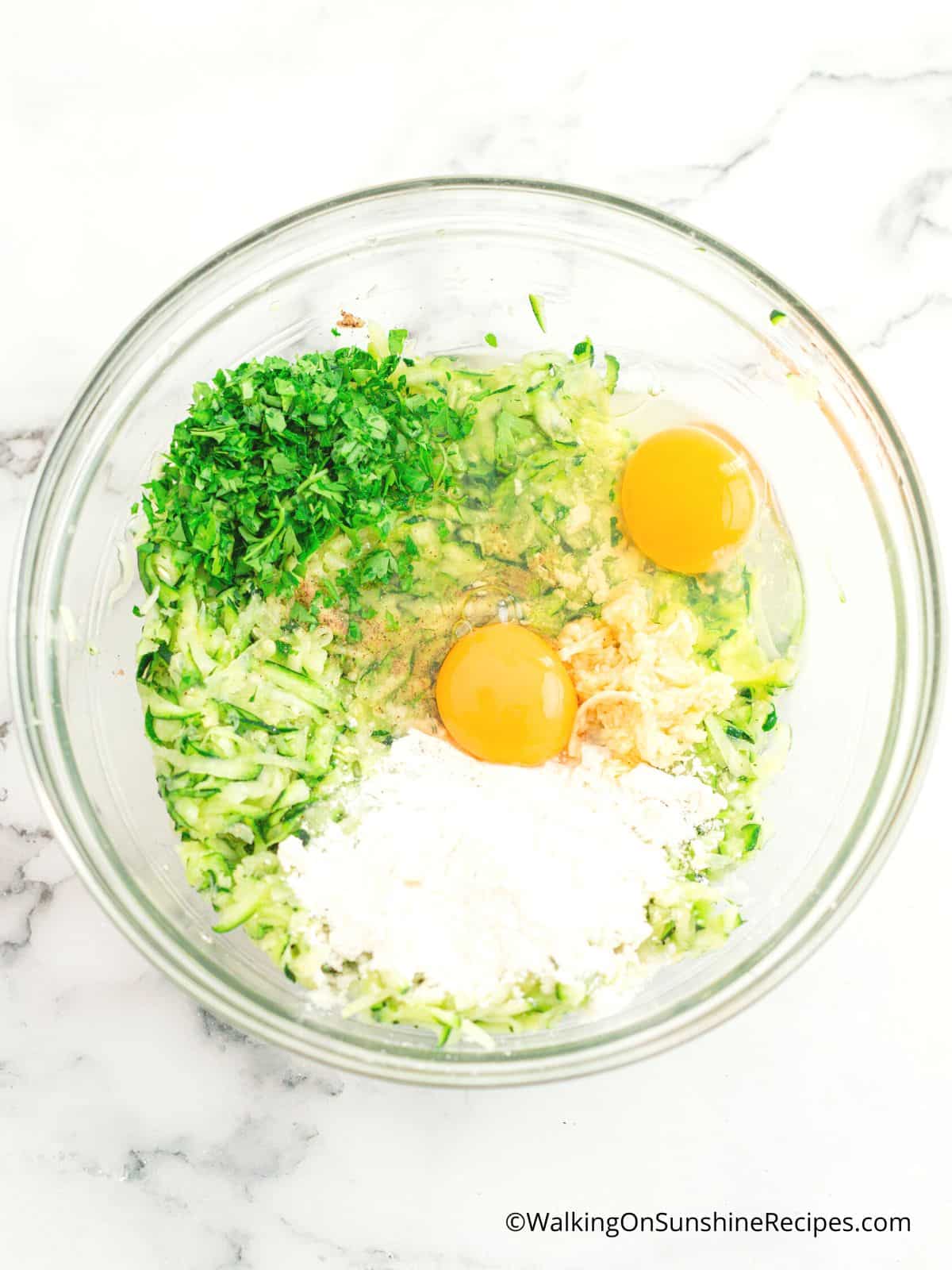Grated zucchini, flour, eggs and parsley in mixing bowl.