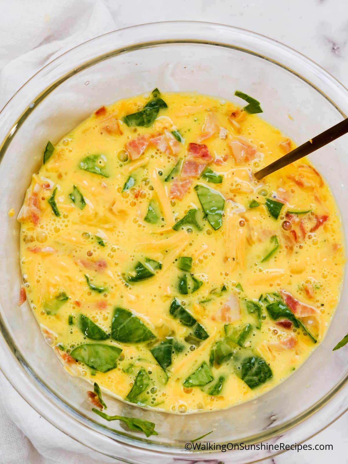 scrambled egg mixture with chopped bacon and spinach.