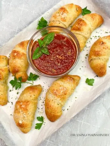 Garlic Butter Crescent rolls on white tray with marinara sauce and parsley.