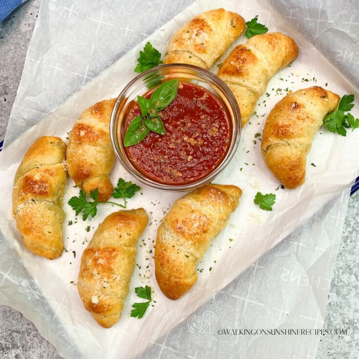 Garlic Butter Crescent rolls on white tray with marinara sauce and parsley.