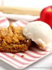 pumpkin apple dump cake served on a red and white striped plate with a scoop of vanilla ice cream