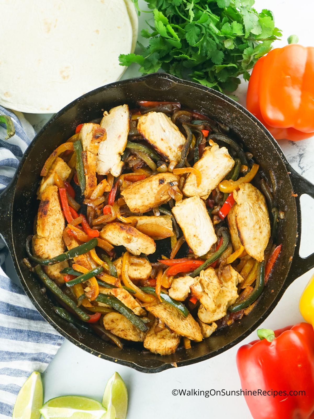 chicken in cast iron skillet with peppers and onions.