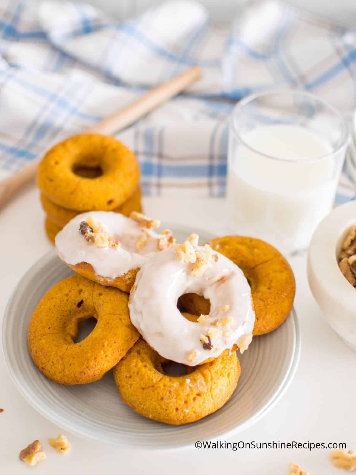 Homemade pumpkin donuts with glaze and without on white plate.