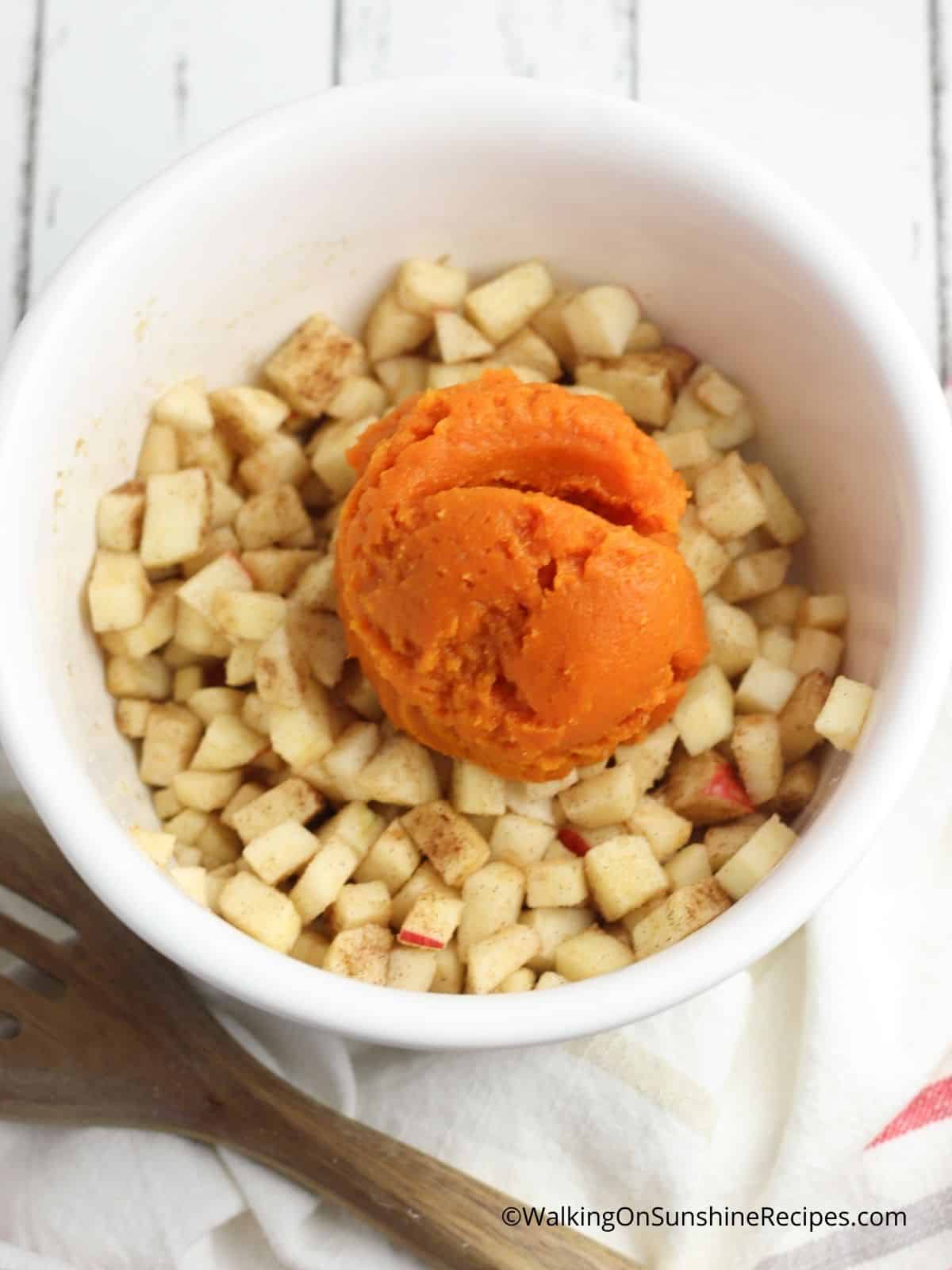 chopped apples with pumpkin puree on top in white bowl.
