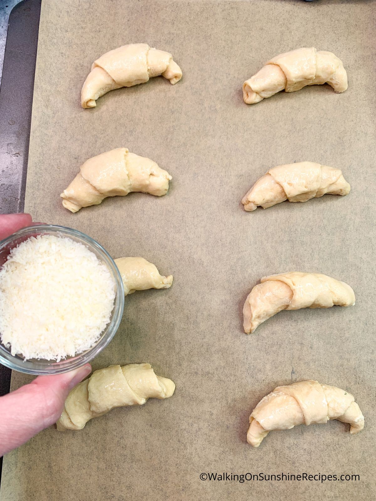 Sprinkle Parmesan chee on top of garlic butter crescent rolls.