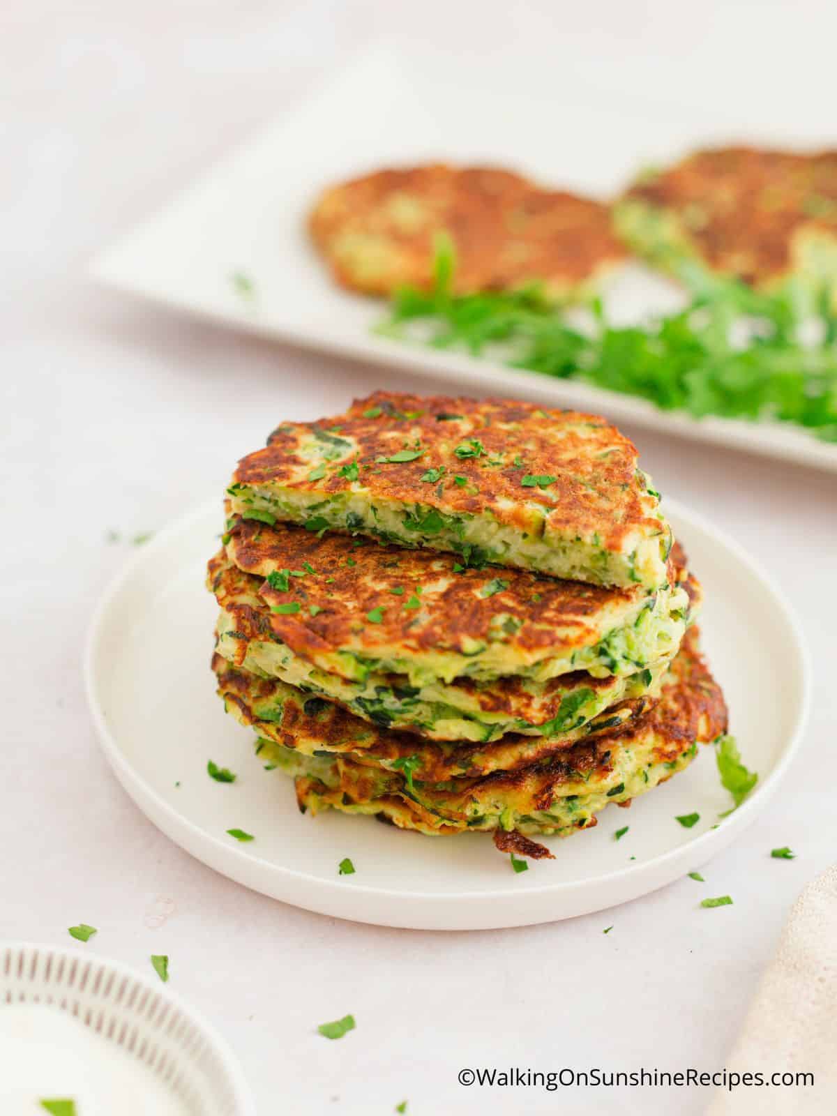 zucchini fritter cut in half on top of a stack of fritters.