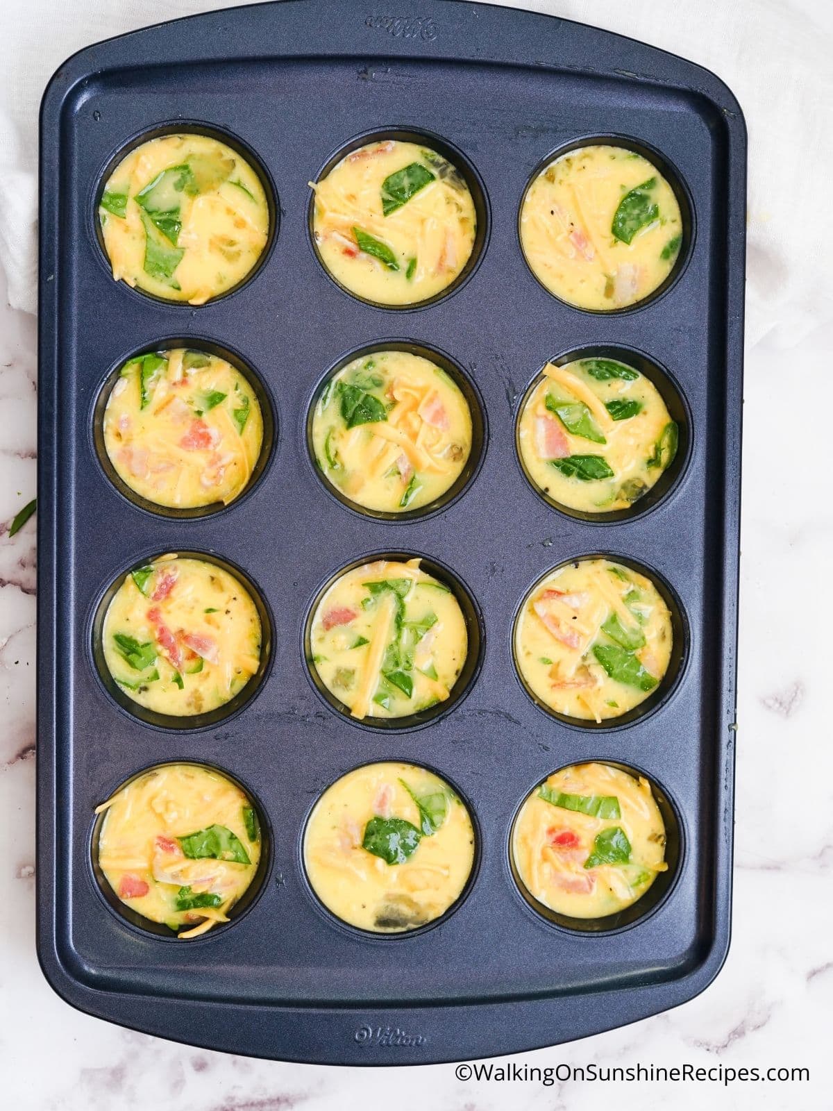 scrambled eggs and bacon in muffin tin before baking.