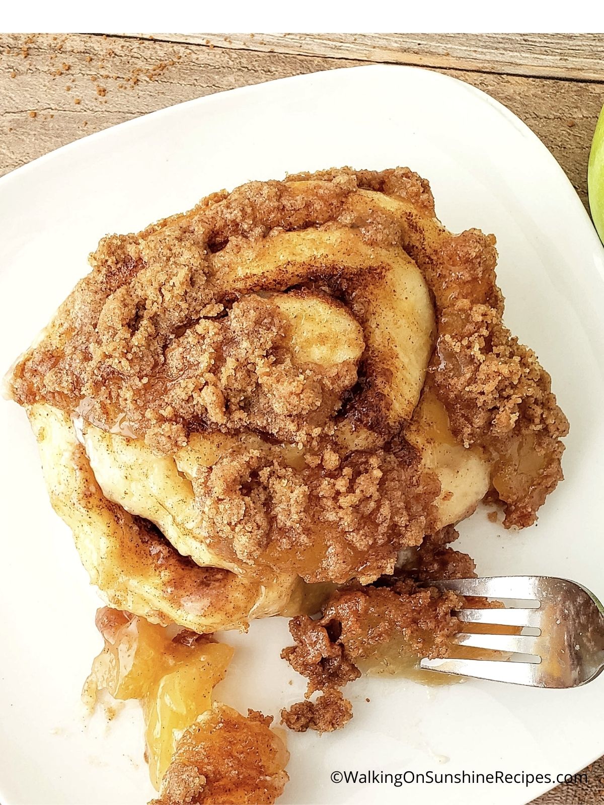 One cinnamon roll with apple pie filling on plate.
