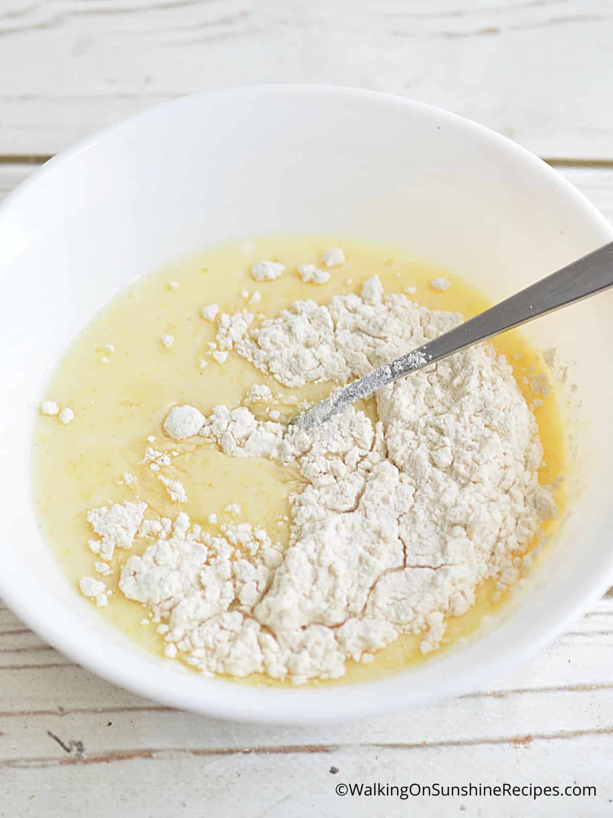 Add vanilla cake mix to wet ingredients in white bowl.