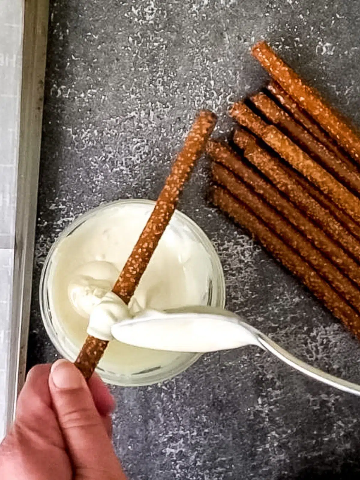 Use a spoon to cover pretzels with melted white chocolate.