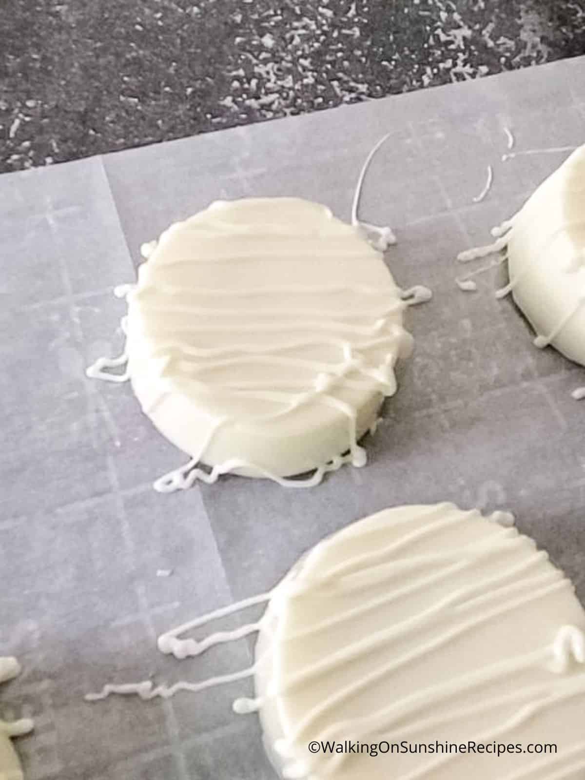 drizzle melted chocolate on top of white chocolate covered Oreo cookies.