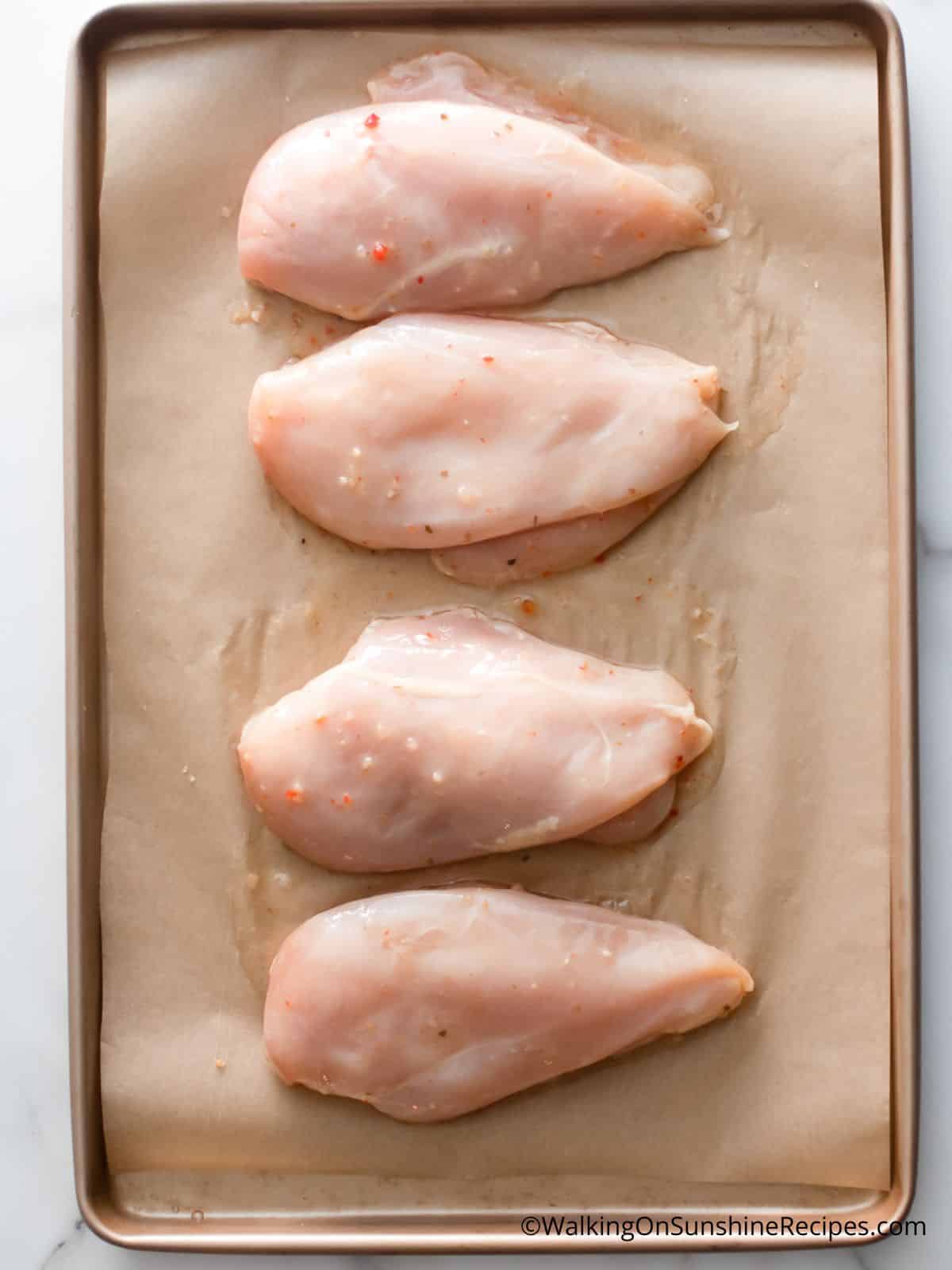 chicken cutlets on baking tray with parchment paper.