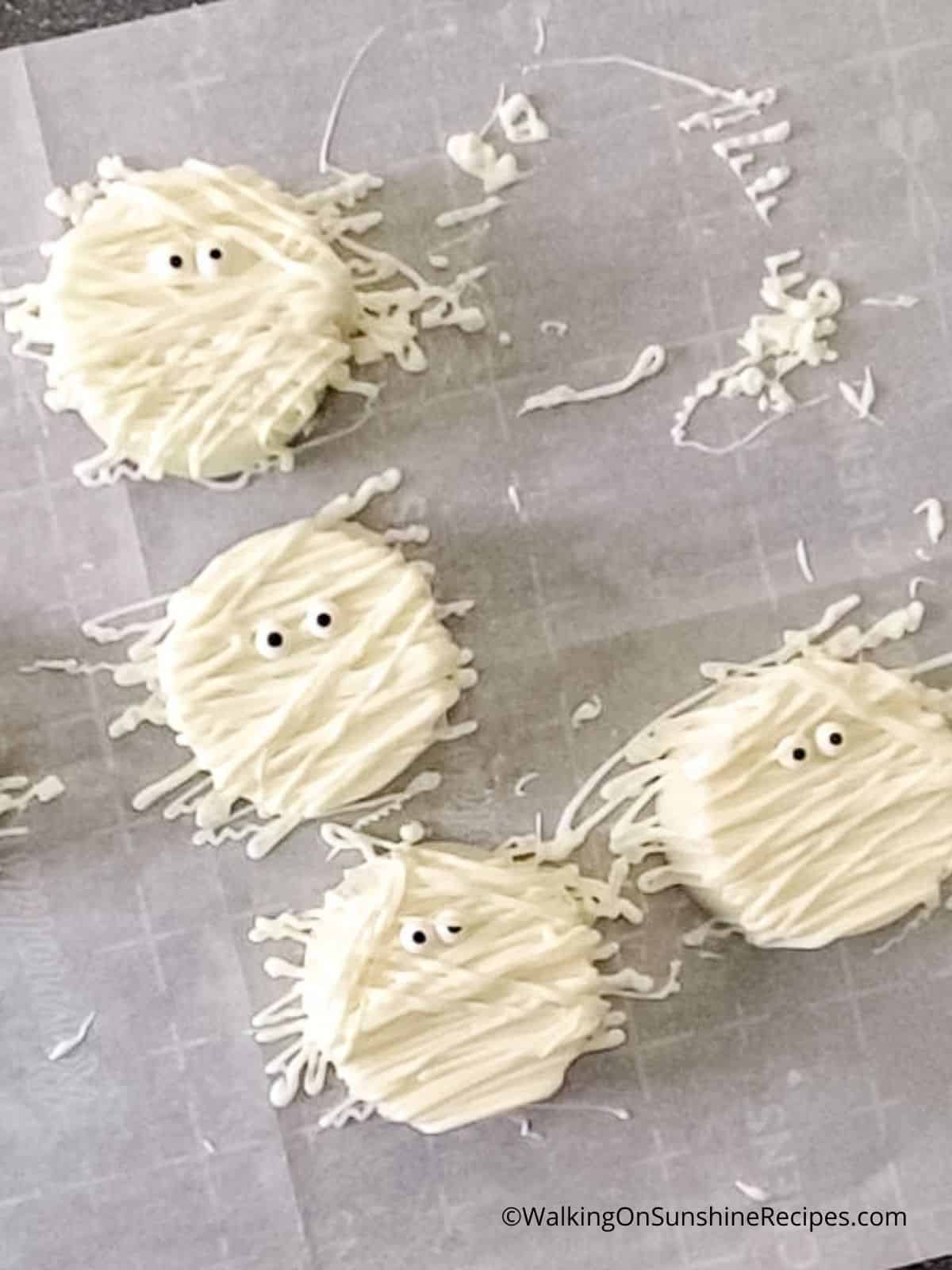 Add candy eyes to white chocolate covered Oreo cookies.