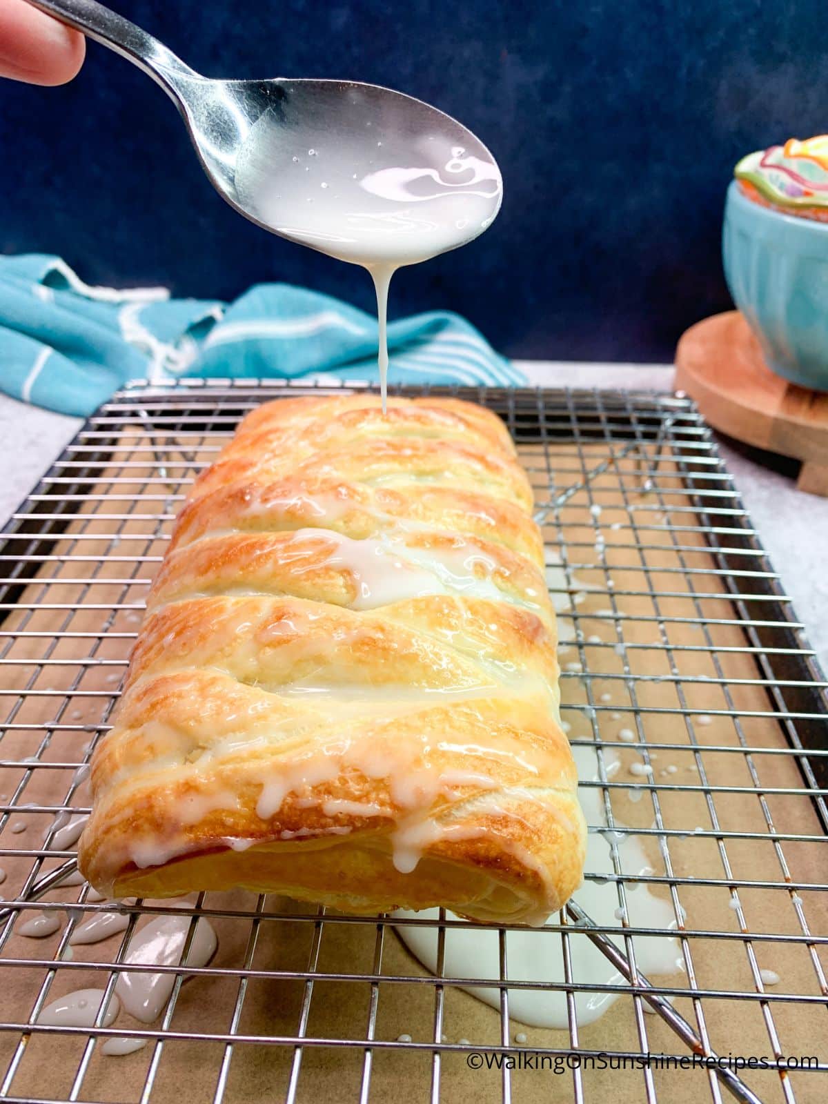 Use a spoon to drizzle the powdered sugar glaze on top of puff pastry danish.