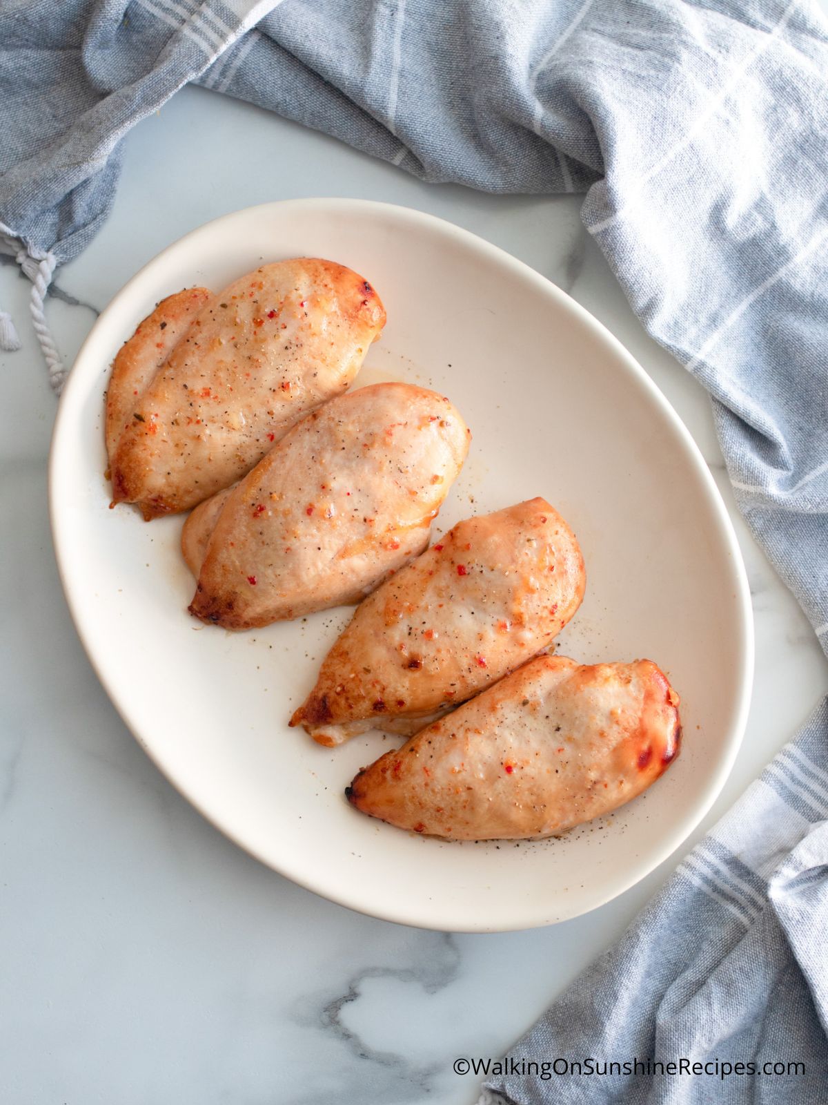 4 pieces of Baked chicken cutlet on white plate.