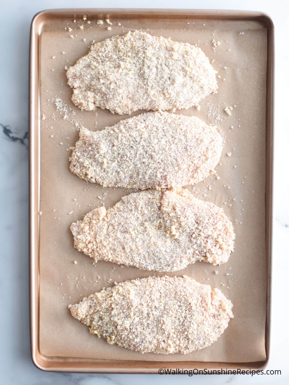 coated chicken cutlets on baking tray.