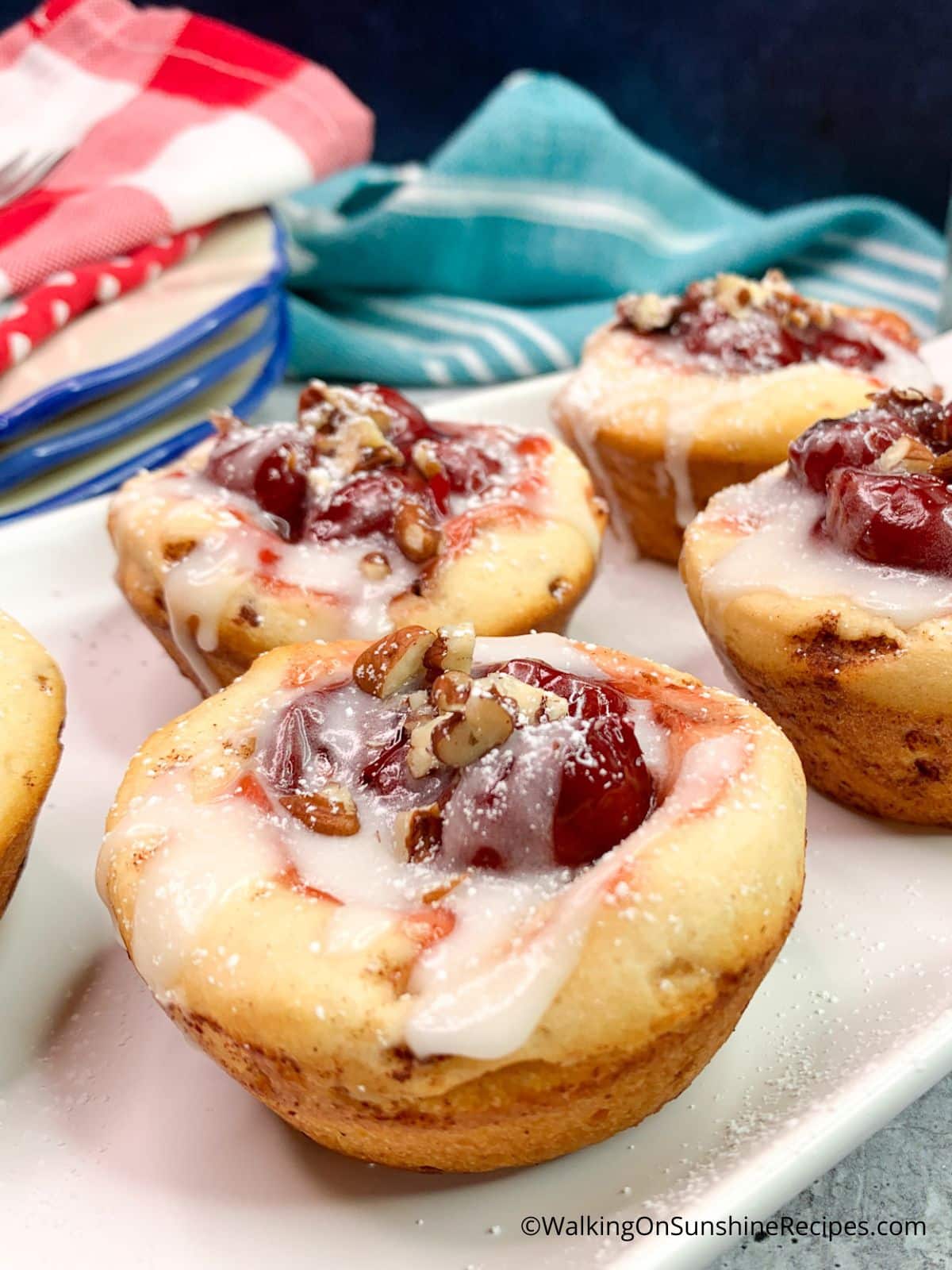 chopped pecans on top of cinnamon roll cups with cherry pie fillling.