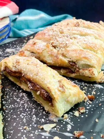 Chocolate puff pastry on tray sprinkled with powdered sugar.