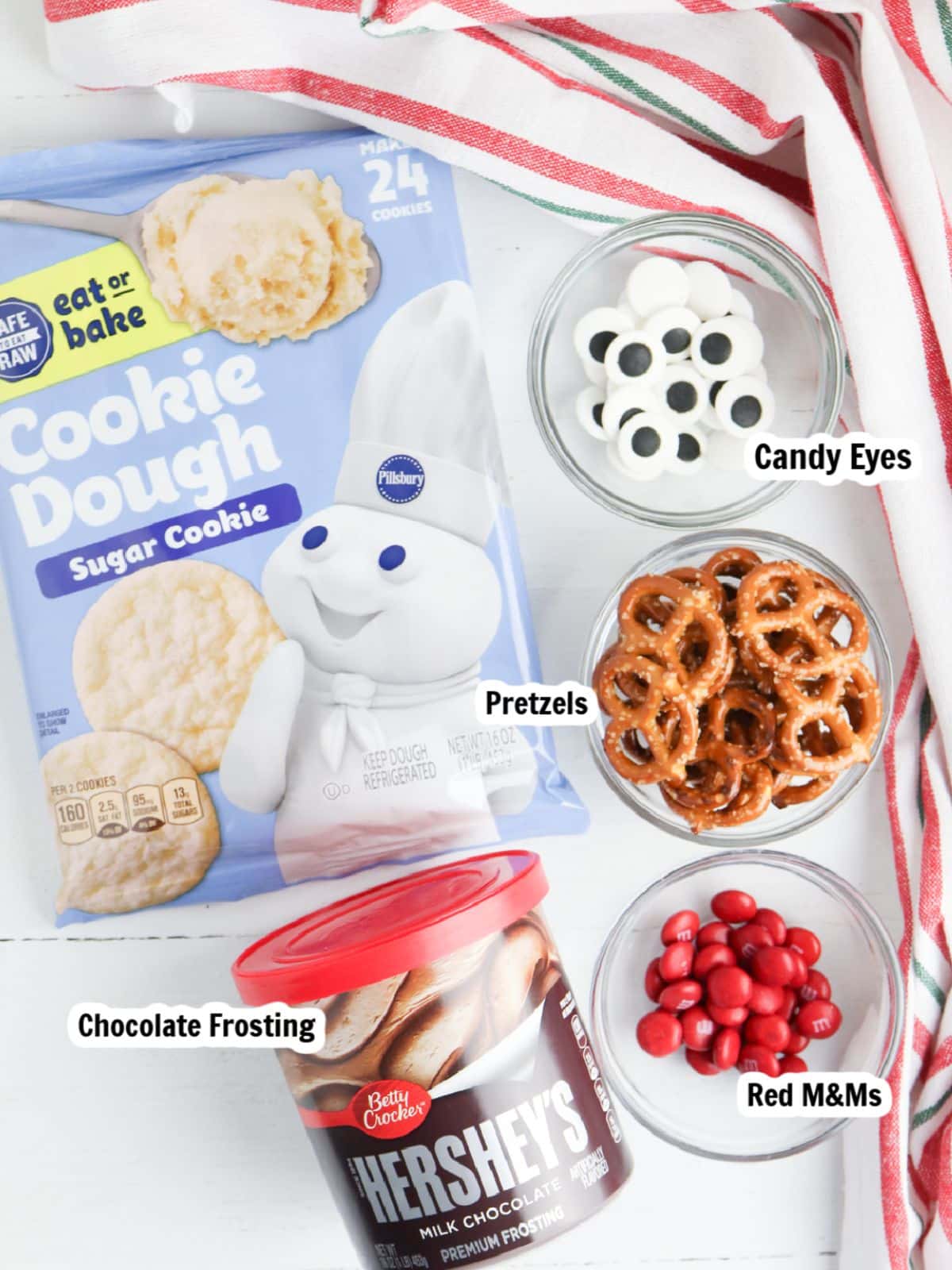 Ingredients, chocolate frosting, red M&Ms, pretzels, candy eyes, refrigerator sugar cookie dough.