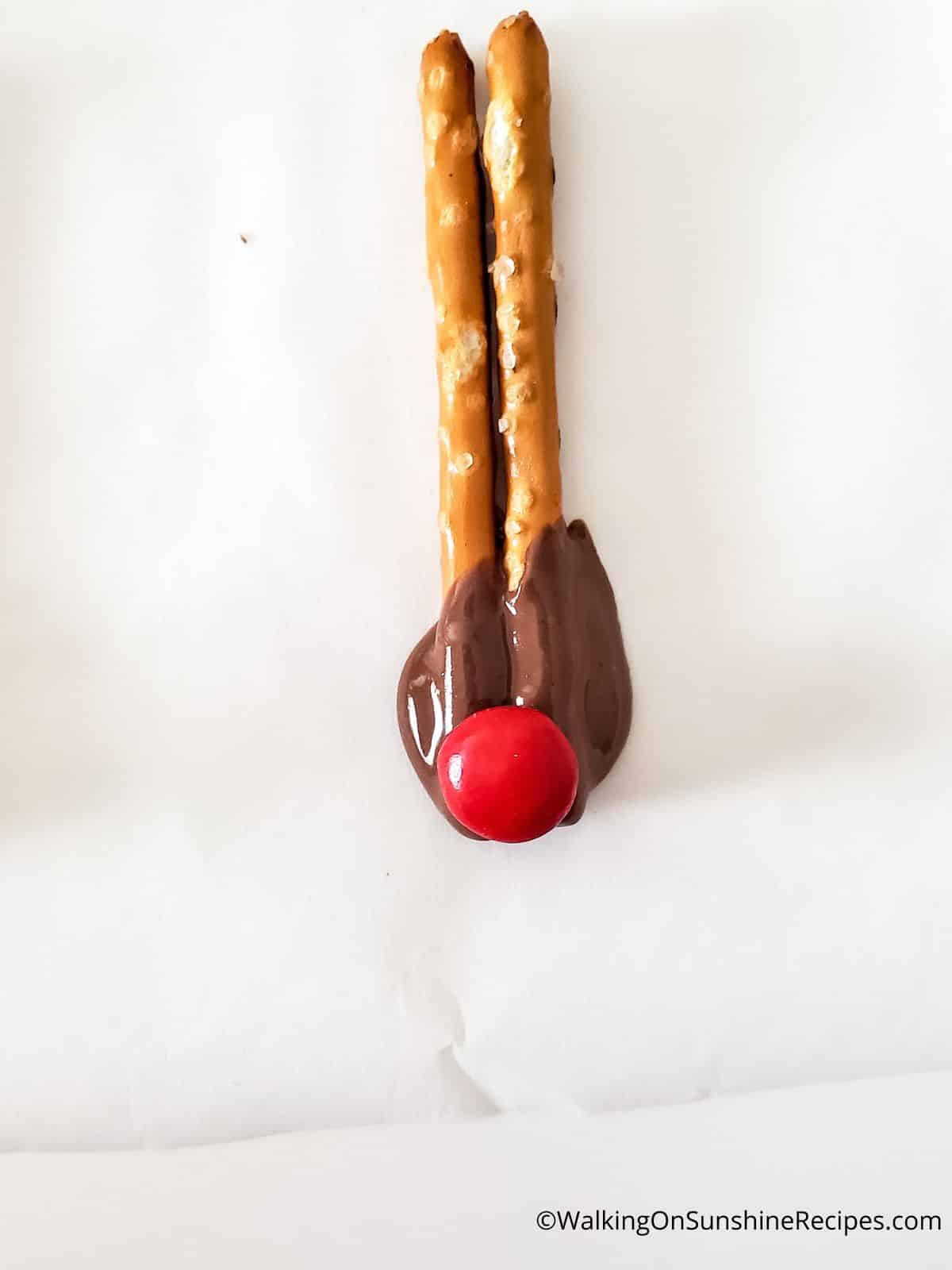 red M&M on top of melted chocolate pretzel sticks.