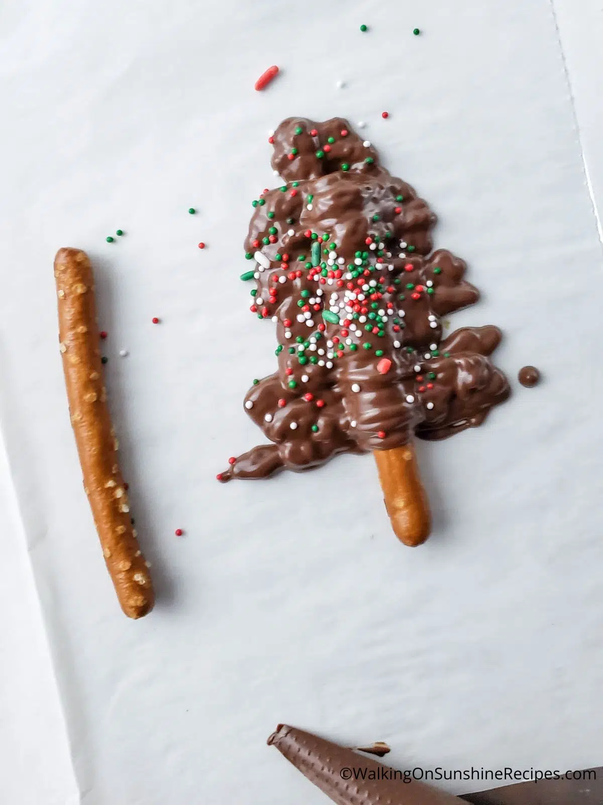 Add sprinkles to chocolate covered pretzel stick.