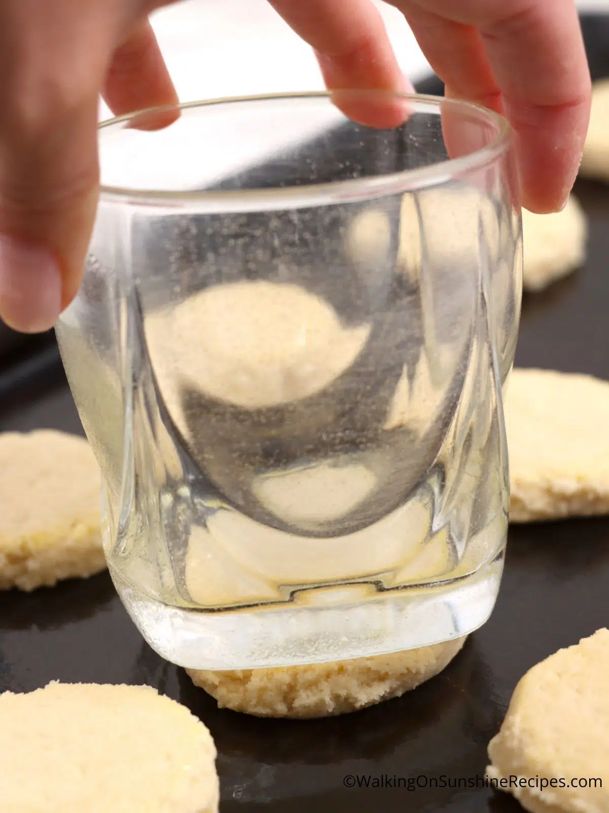 press sugar cookie dough balls flat using a glass.