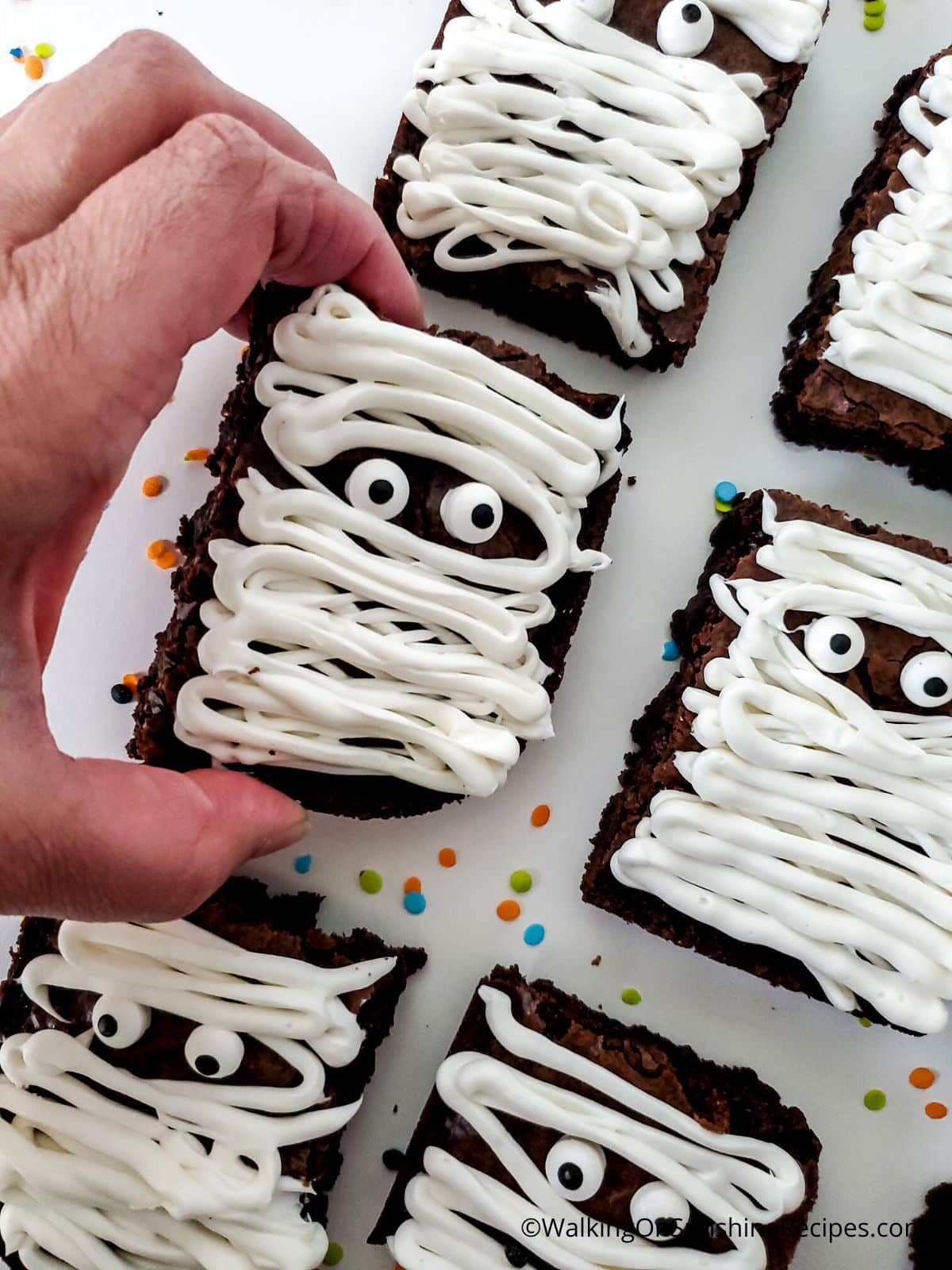 Lifting up one mummy brownie from serving tray.