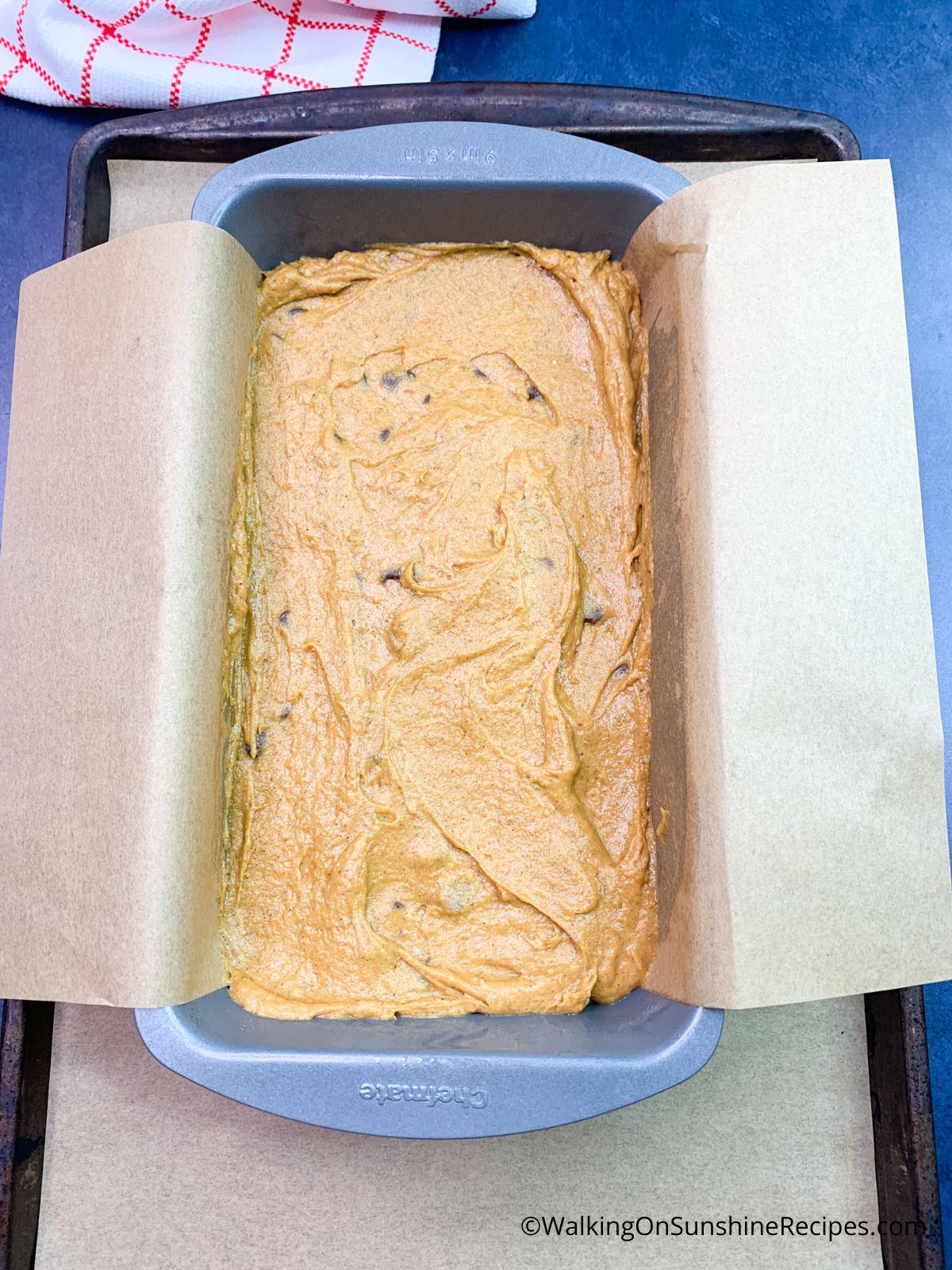 pumpkin bread batter in loaf pan lined with parchment paper.