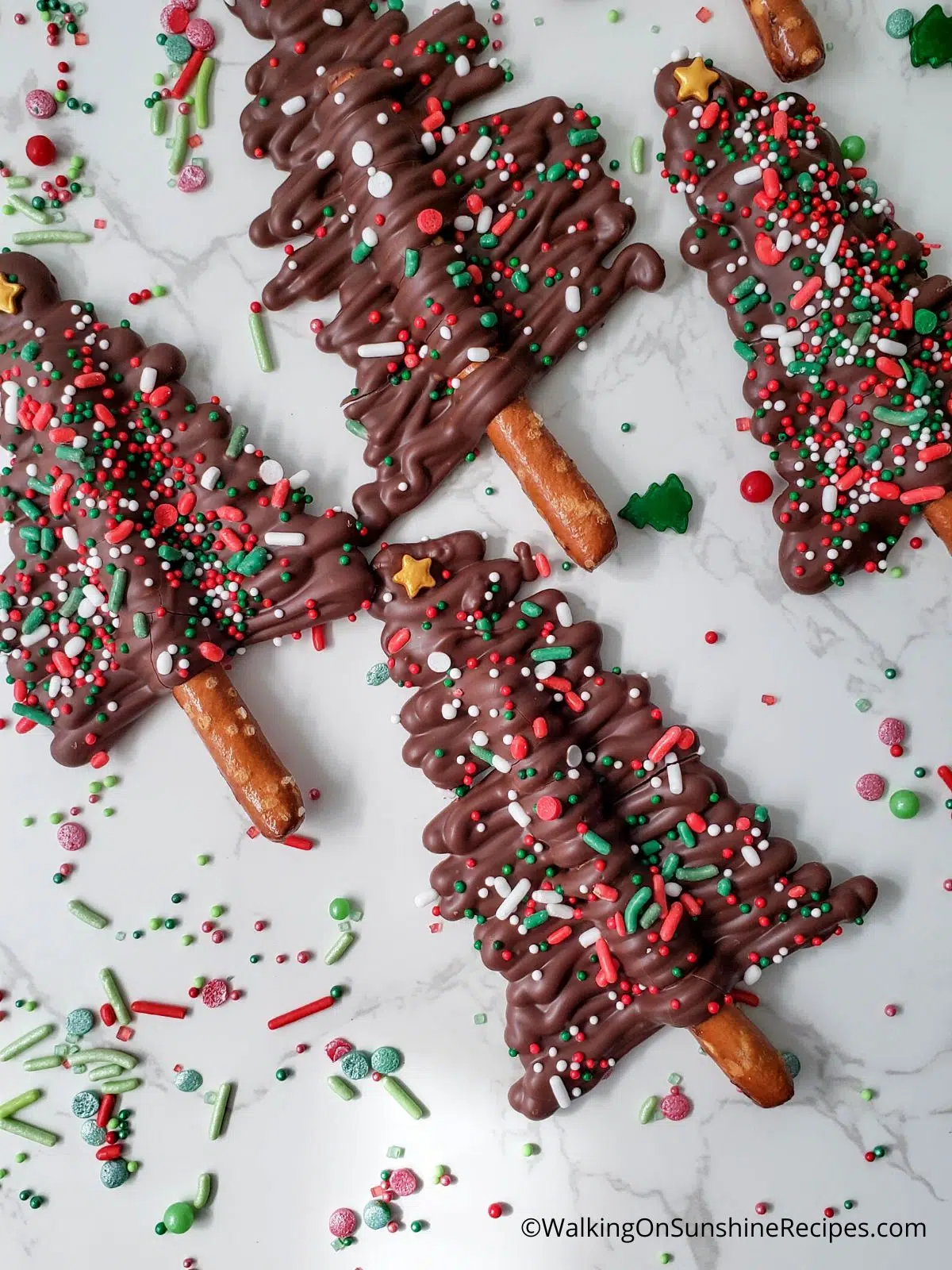 Chocolate pretzel sticks made into trees with sprinkles and gold star.