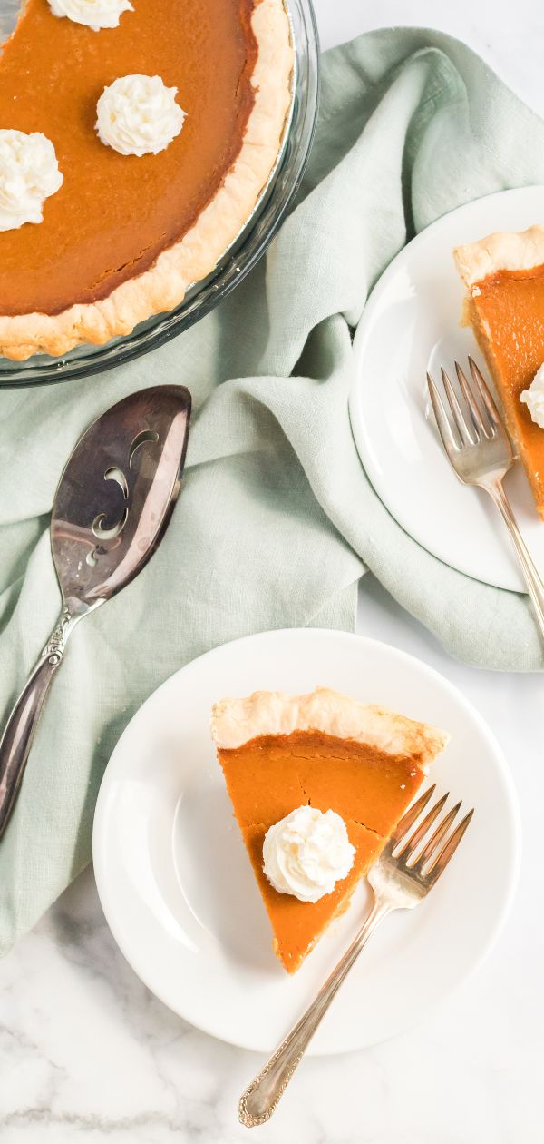 slices of pumpkin pie served on white plates.