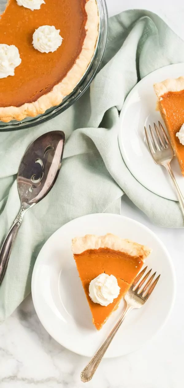 slices of pumpkin pie served on white plates.