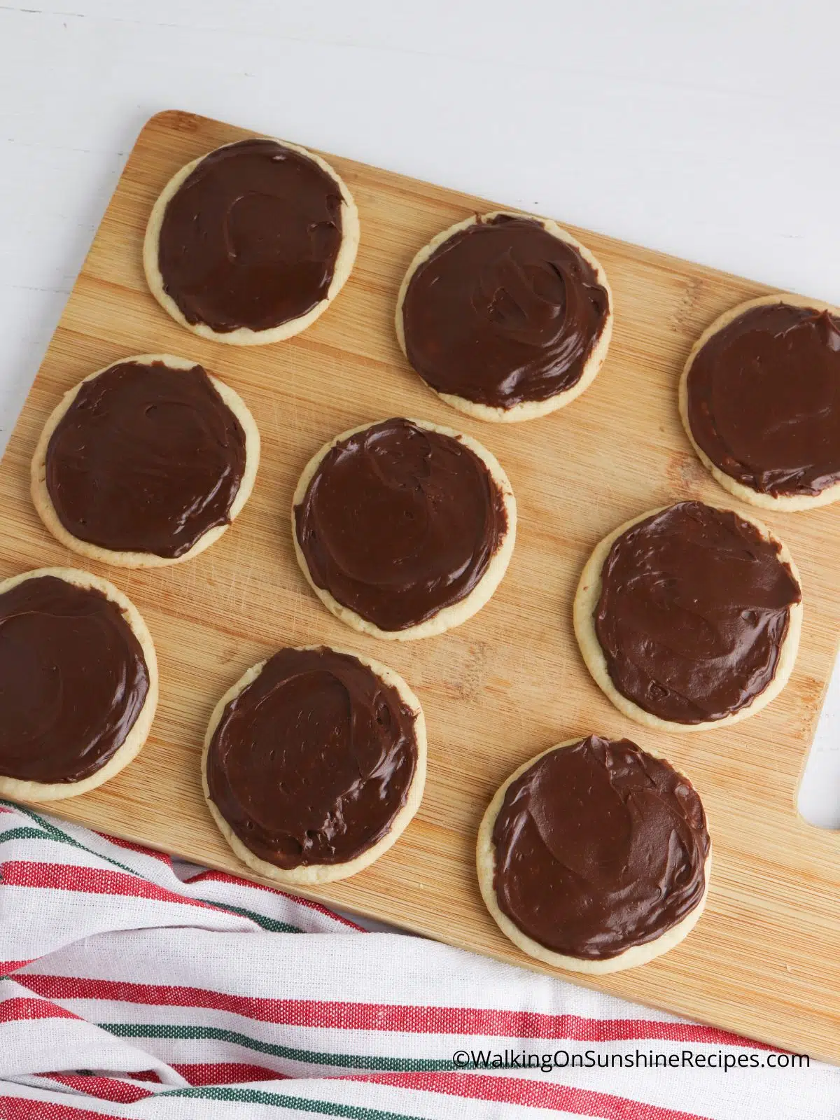 spread chocolate frosting on baked sugar cookies.