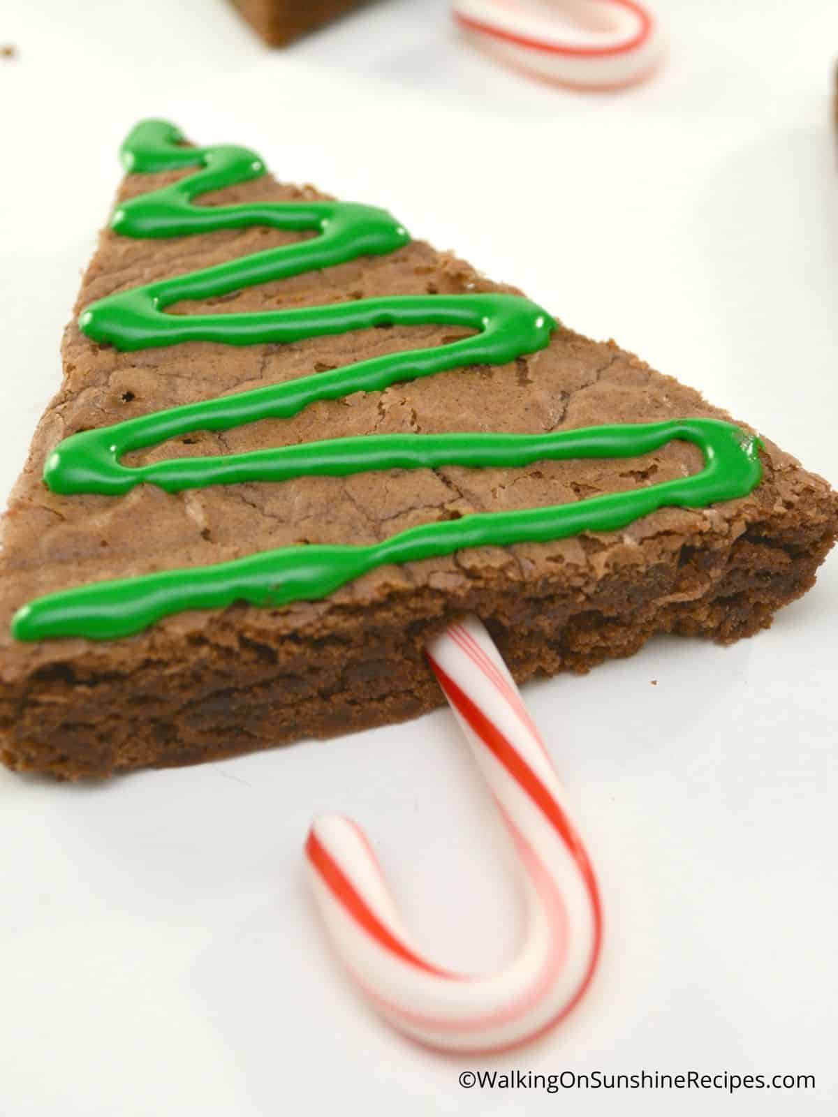 Add frosting and candy cane to baked brownie.