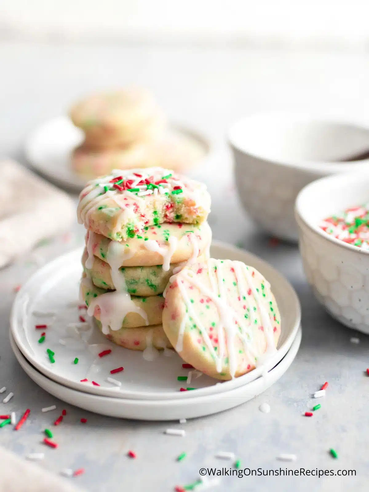 Stacked Christmas cookies with sprinkles and glaze on plate.