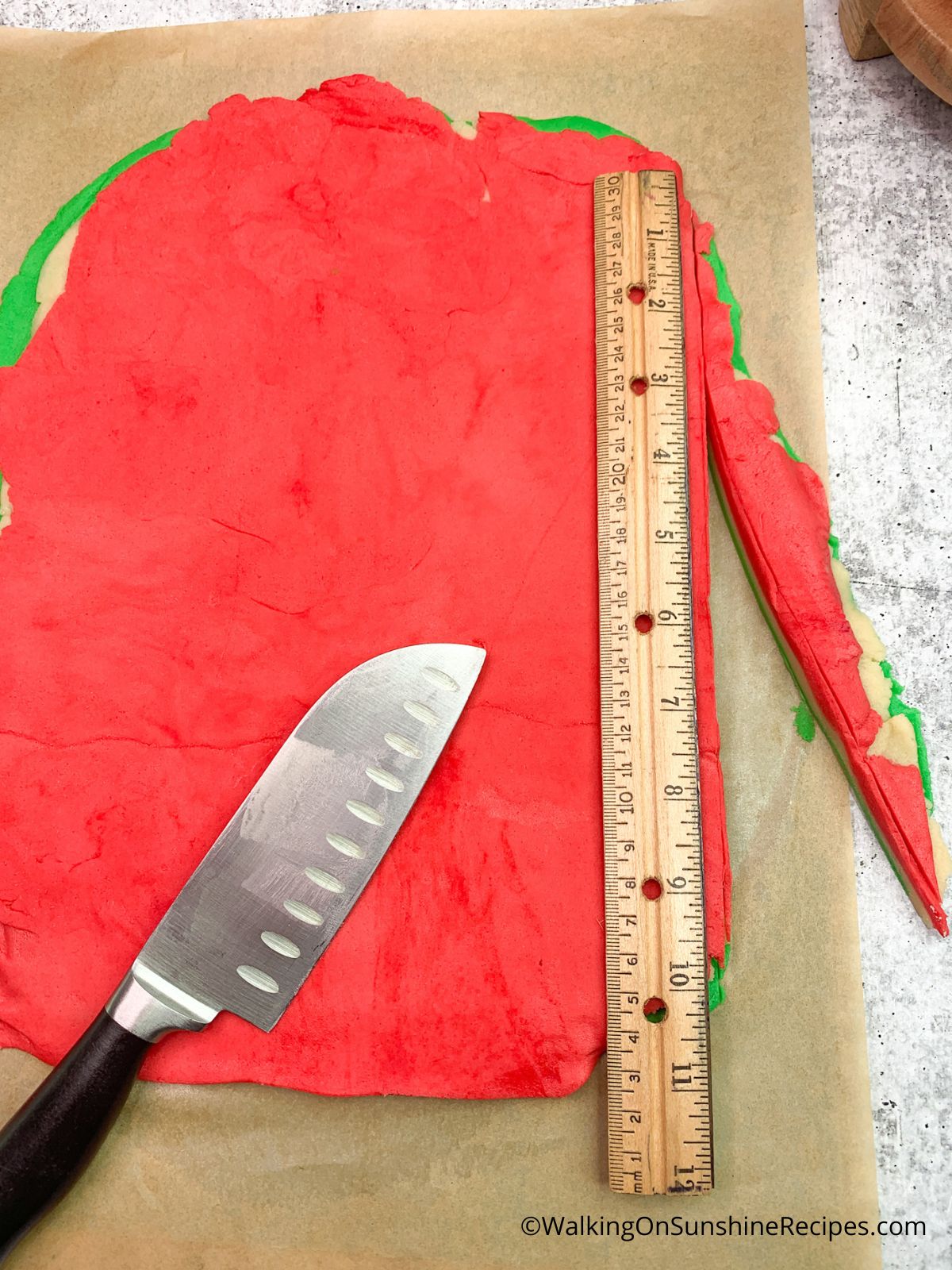 Slicing cookie dough with knife and ruler.
