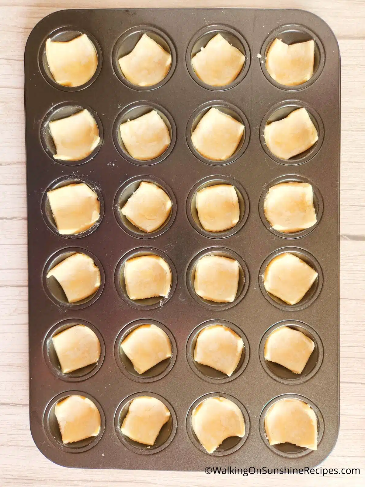 Puff pastry squares in muffin pan.