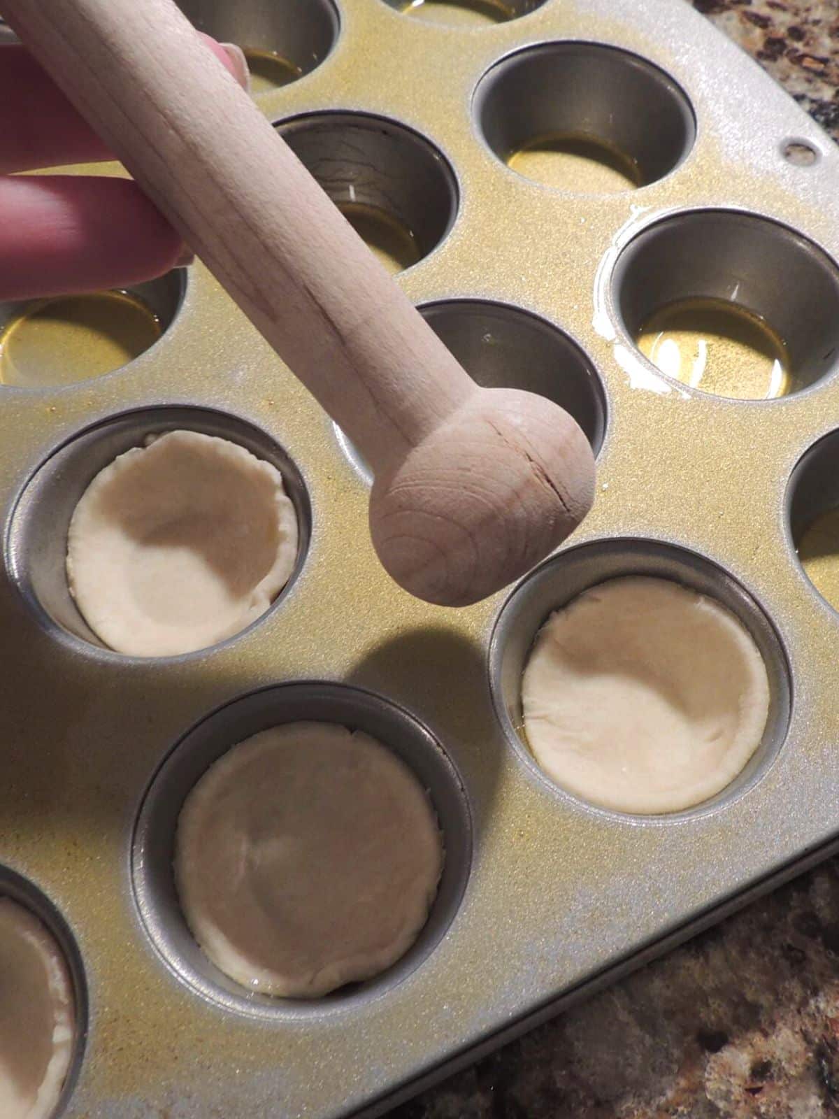Place cut out pie crust dough in mini muffin pan.