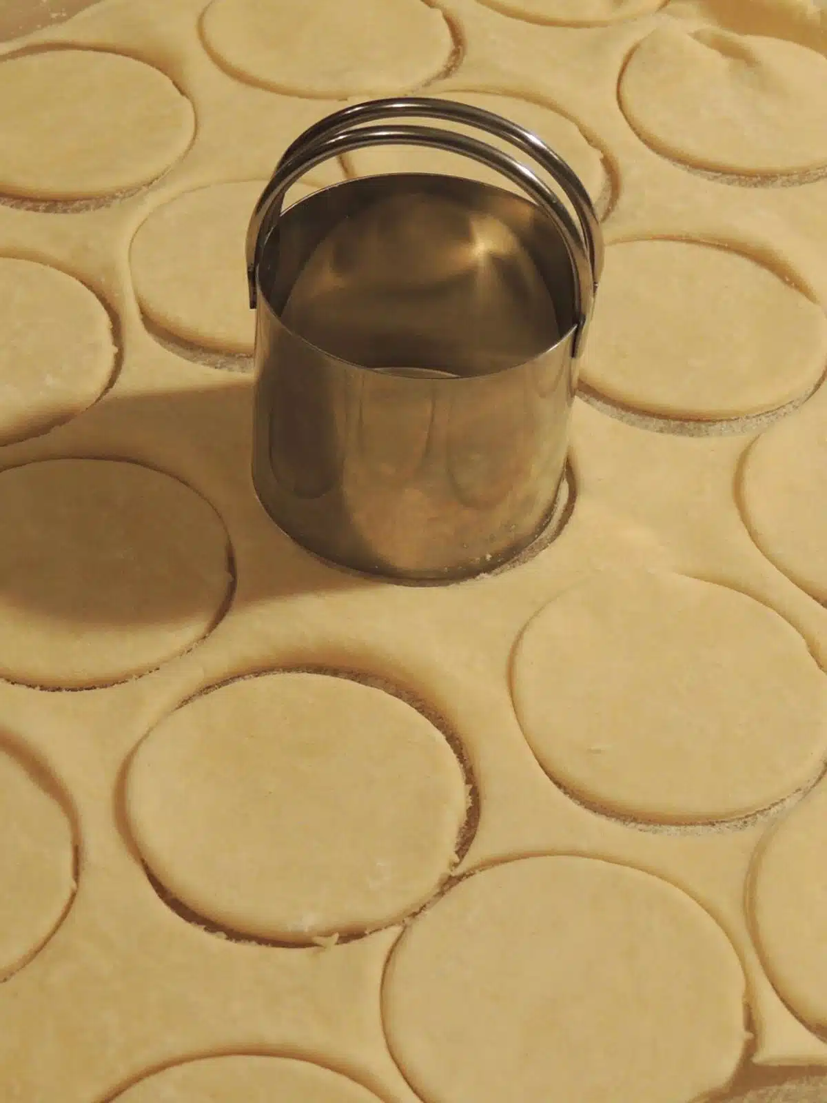 Use a biscuit cutter to cut out round shapes in pie crust dough.