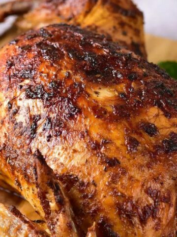 A roasted chicken on a wooden board.