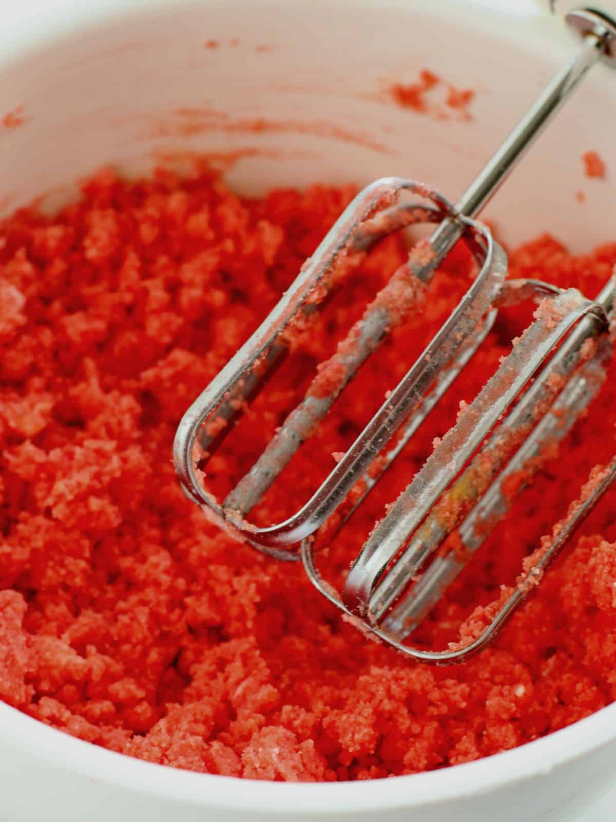 electric mixer with red cake mix cookie batter.