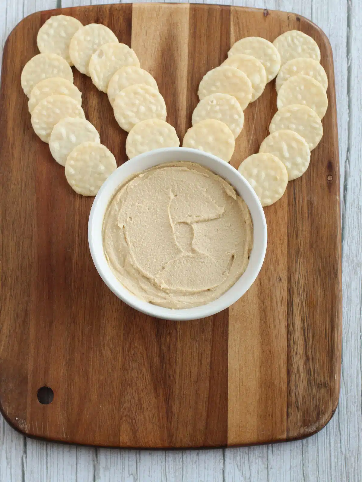 Cracker bunny ears and bowl of hummus on a wooden board